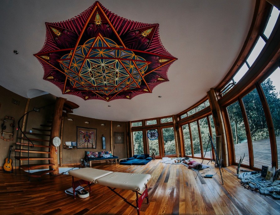 Circular wellness room with mandala ceiling, wood floors, and forest views through curved windows